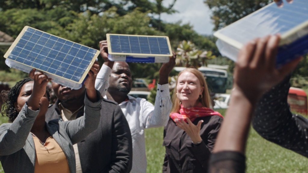 Students and faculty from Kamuzu University of Health Sciences in Malawi hold up SolarSPELL devices to the sun to see how they charge, as SolarSPELL director Laura Hosman talks with them about the technology.