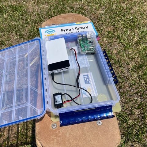 An open SolarSPELL library, displaying, clockwise from top left, its battery, raspberry pi and converter.