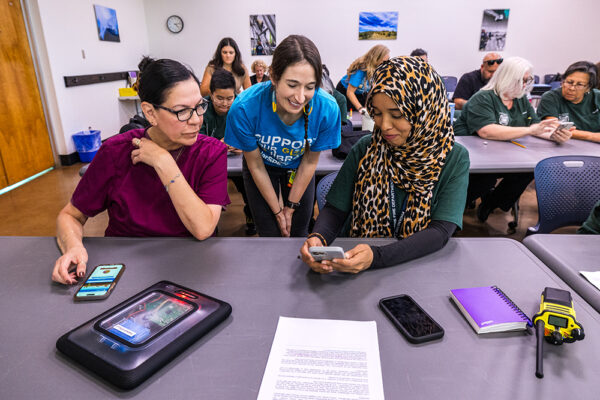 20240918 - SolarSPELL training PFD - Phoenix

The image is fully released; the model release is on file in Media Relations & Strategic Communications.

Crisis response team members, Rose Escudero, left, and Najma Aidarus work with SolarSPELL's Cassie Barrett, to download content from the nearby SolarSpell training device in one of two training sessions with Phoenix Fire Department’s Community Assistance Program members on Wednesday, September 18, 2024, at the department’s special operations in south Phoenix. The nearly 20 employees learned how to help victims of emergencies and how to download curated content to their smartphones, tablets or computers. The remodeled crisis response library is colorful, illustrated and rewritten in English or Spanish to a fifth-grade level. The victims can also download content from the ASU SolarSPELL unit for children, including art, games and movies, to distract them from the emergency. Research studies show distraction greatly aids youngsters in traumatic situations. Photo by Charlie Leight/ASU News